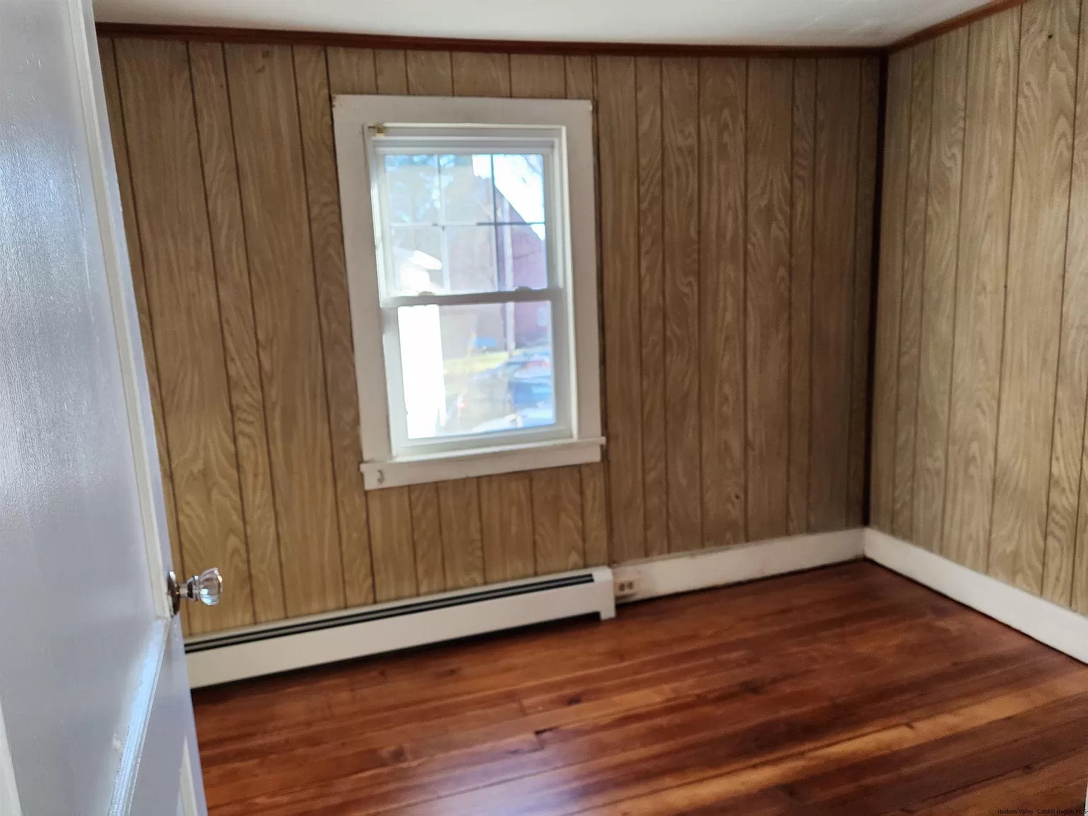 Aged faux wood paneling in bedroom