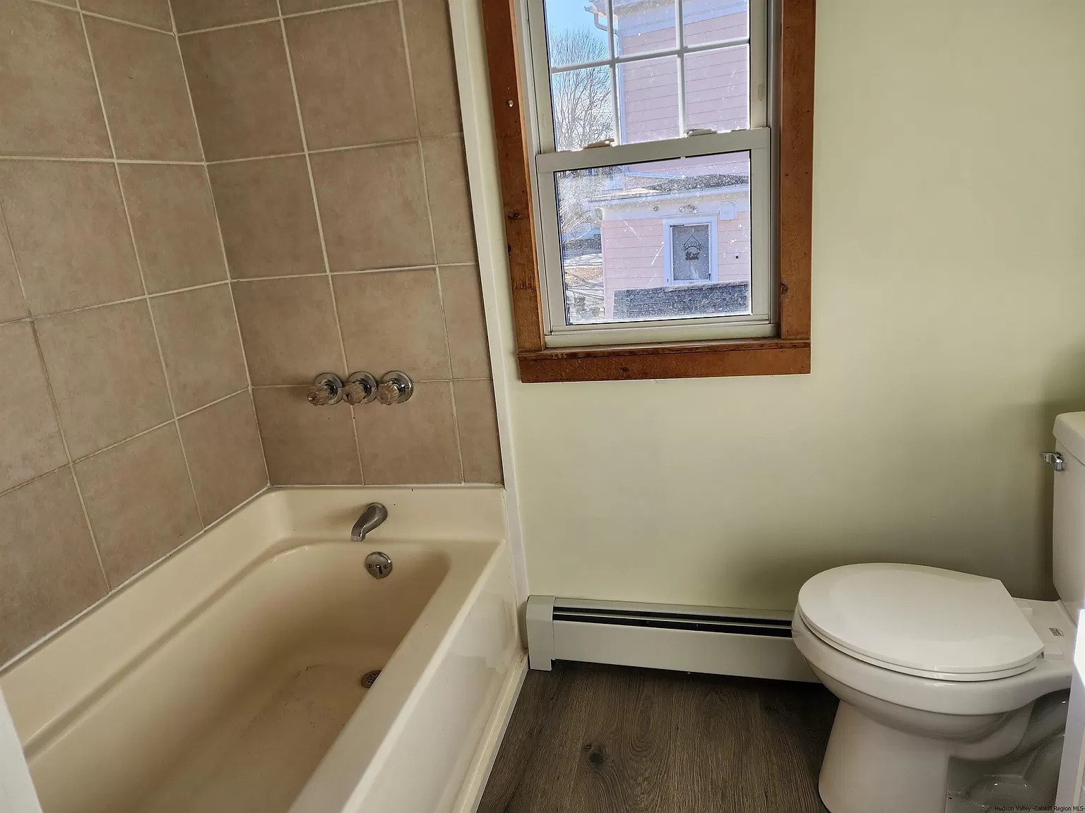 Built-in bathtub with toilet and wood-trimmed window